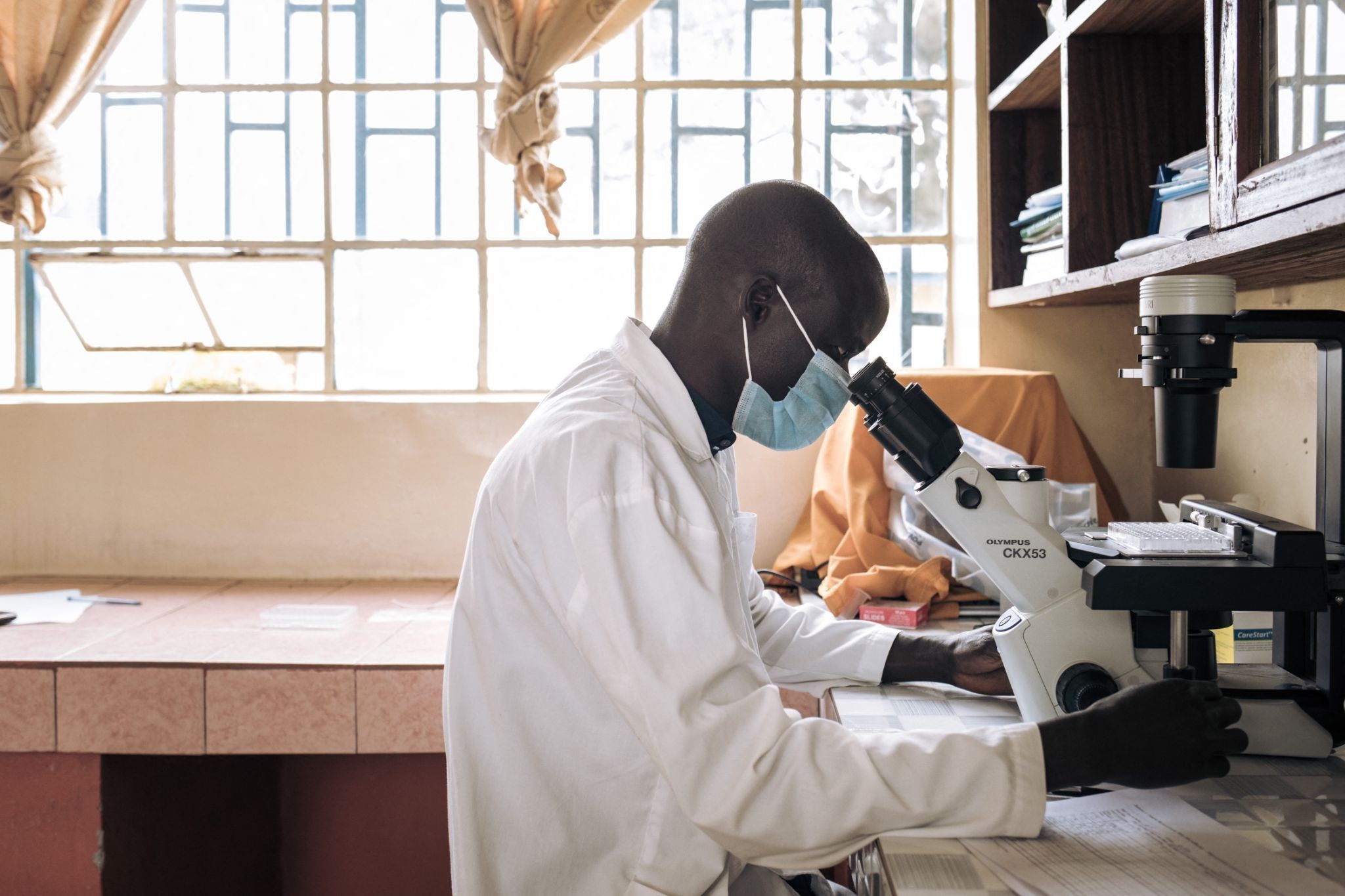 A lab technician looks into a microscope in DR Congo.