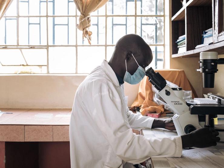 A lab technician looks into a microscope in DR Congo.