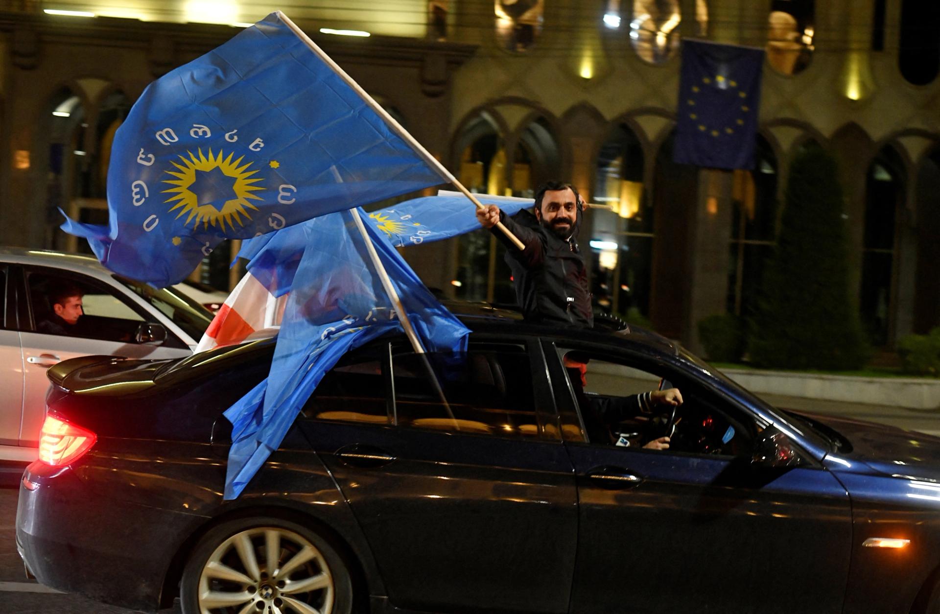 A supporter of the Georgian Dream party waves the party’s flags from a car after the announcement of exit poll results in parliamentary elections, in Tbilisi, Georgia.