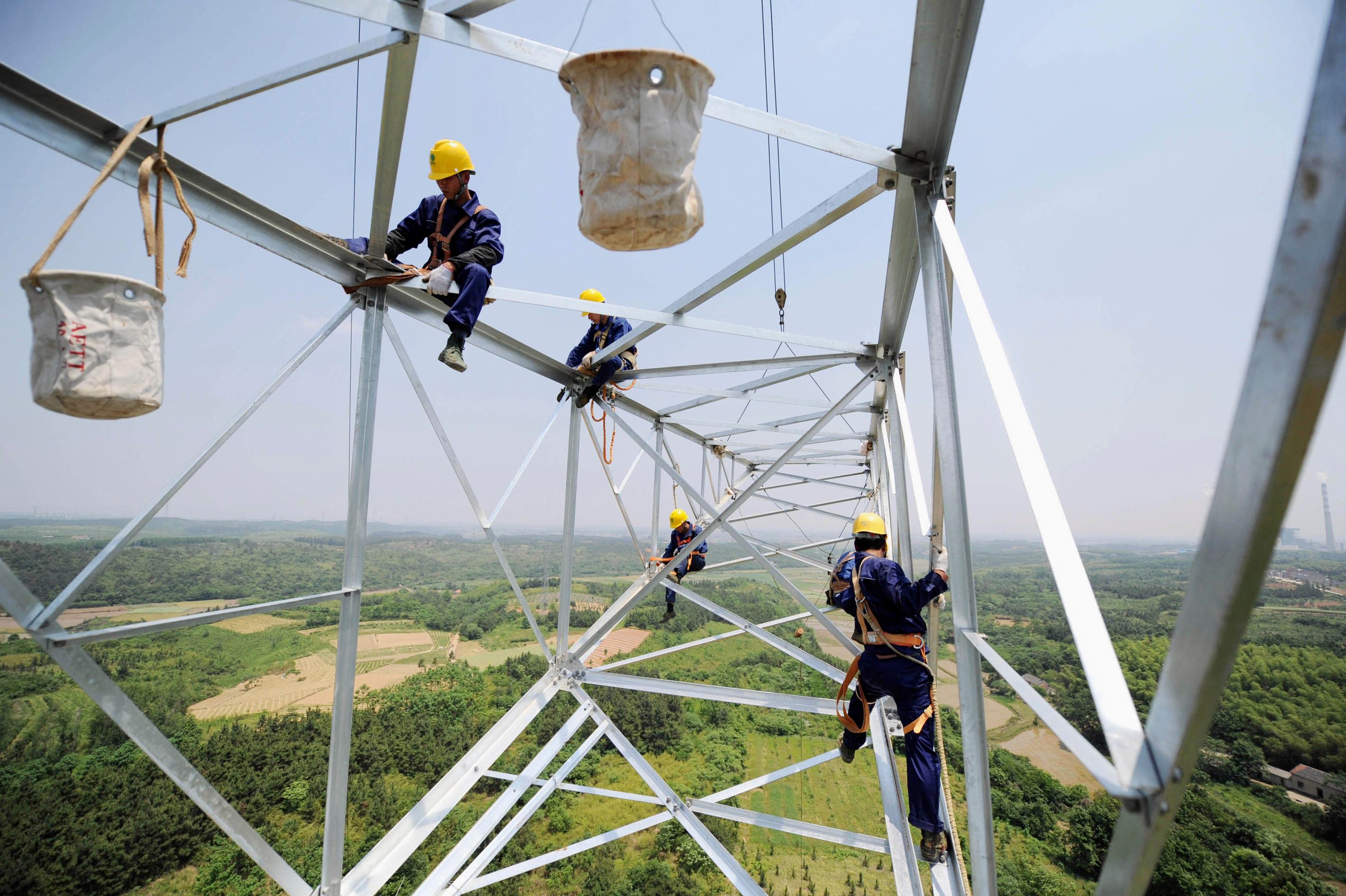 Workers install a high-voltage electricity pylon in China’s Anhui province.