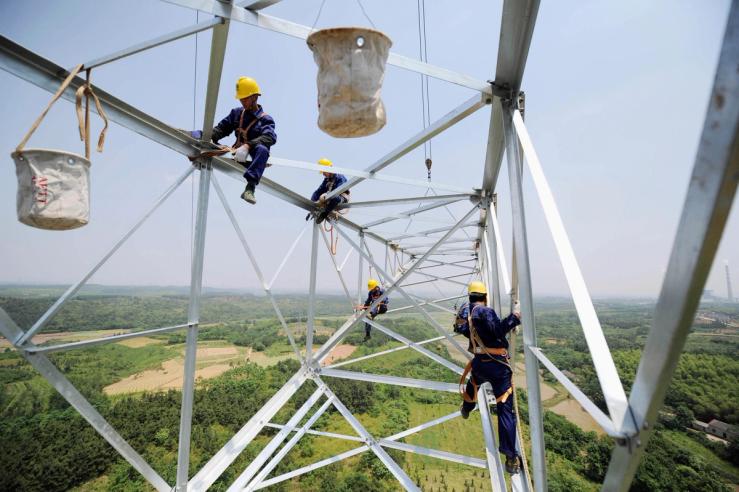 Workers install a high-voltage electricity pylon in China’s Anhui province.