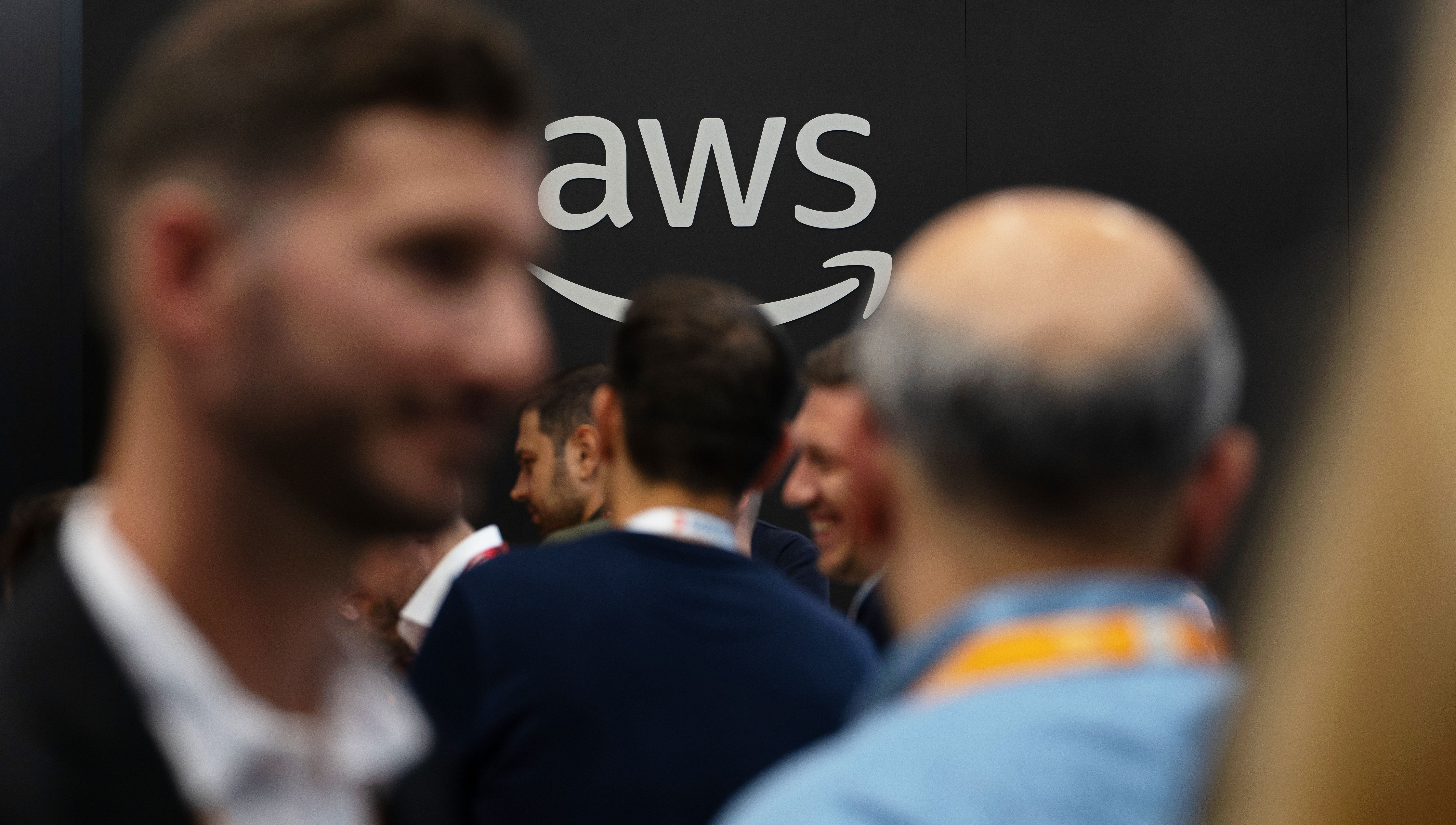An AWS logo with people standing in front.