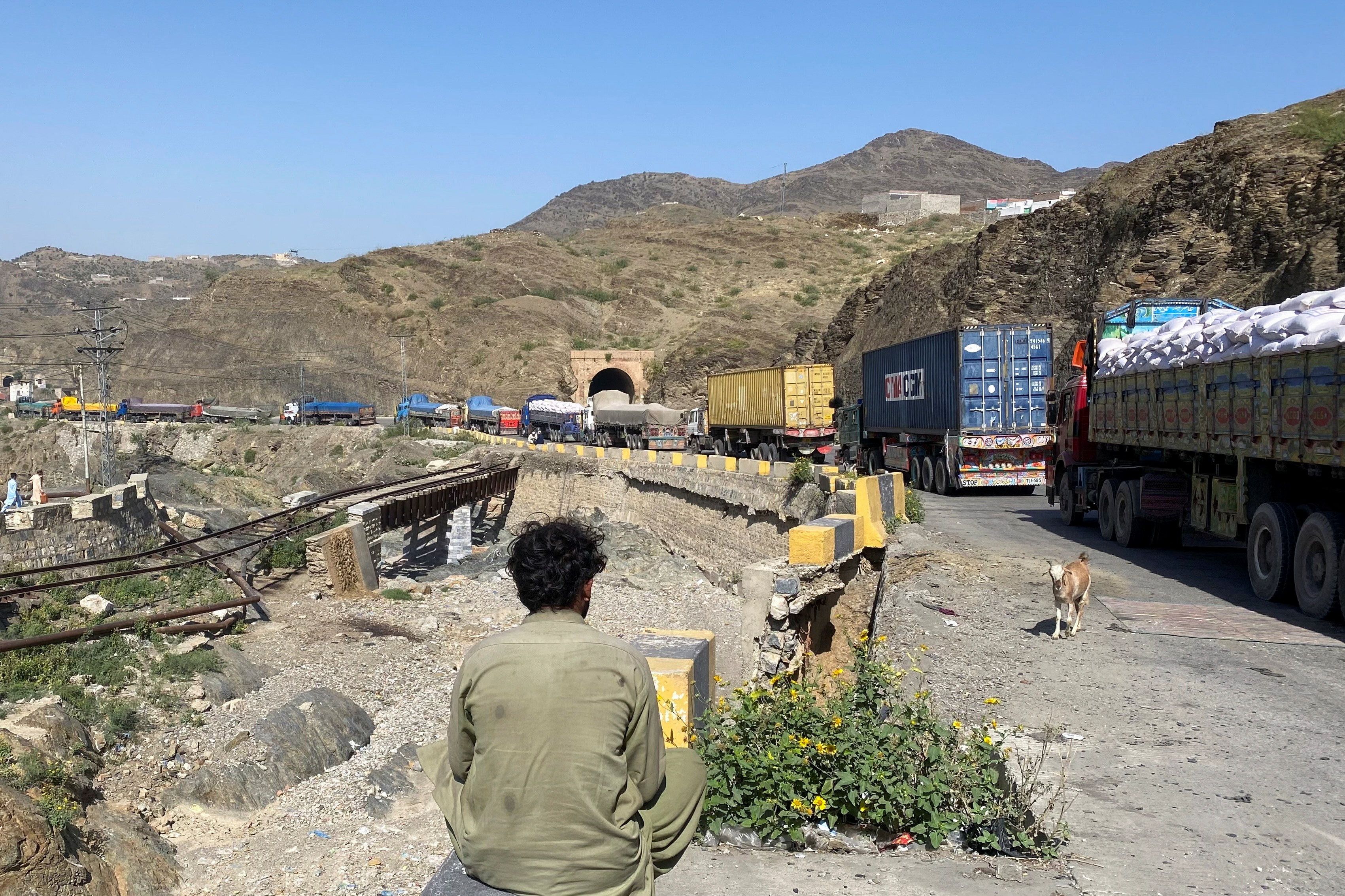 A man sits next to trucks parked at the Torkham border crossing