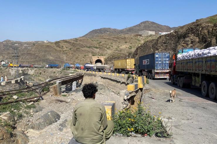 A man sits next to trucks parked at the Torkham border crossing