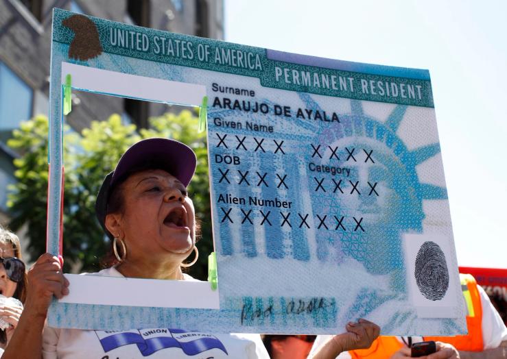 A woman holds a replica green card