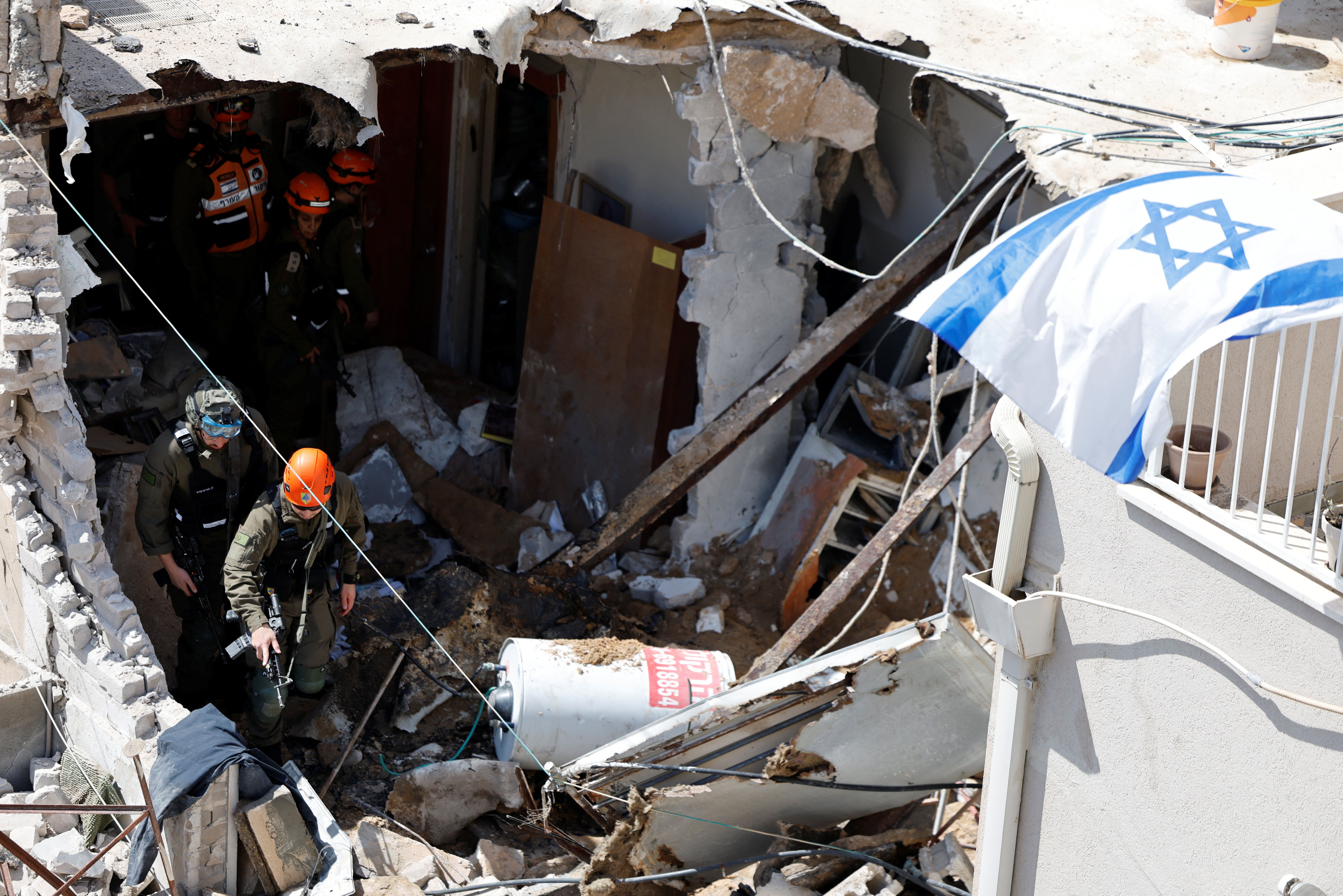 Israeli soldiers inspect the site of a damaged building following barrages of Iranian missiles in Tel Aviv