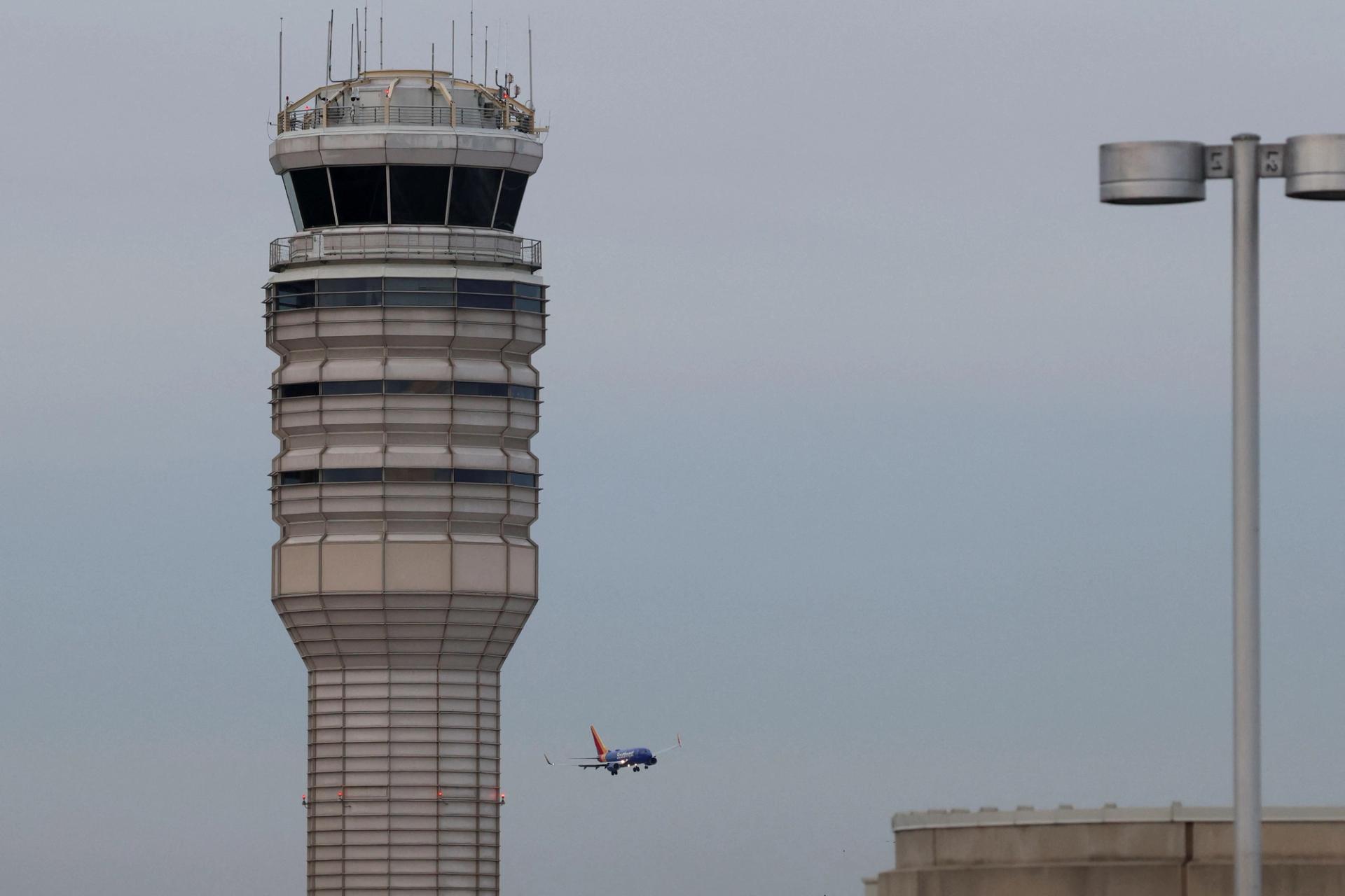 A plane flies next to an air traffic control near Ronald Reagan Washington National Airport, 2025.