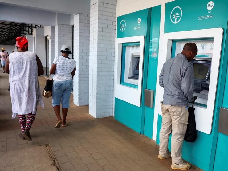 A customer uses an ATM outside a branch of South Africa’s First National Bank (FNB) at the Dobson Point Shopping Centre, in Soweto, South Africa.