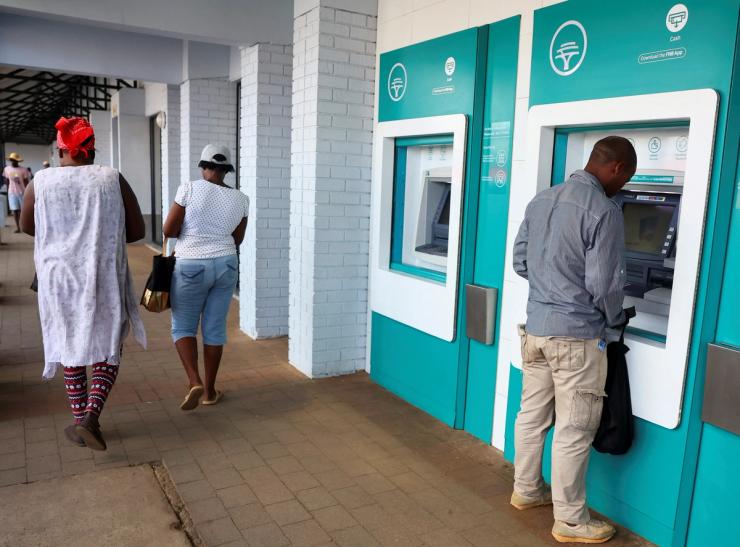 A customer uses an ATM outside a branch of South Africa’s First National Bank (FNB) at the Dobson Point Shopping Centre, in Soweto, South Africa.