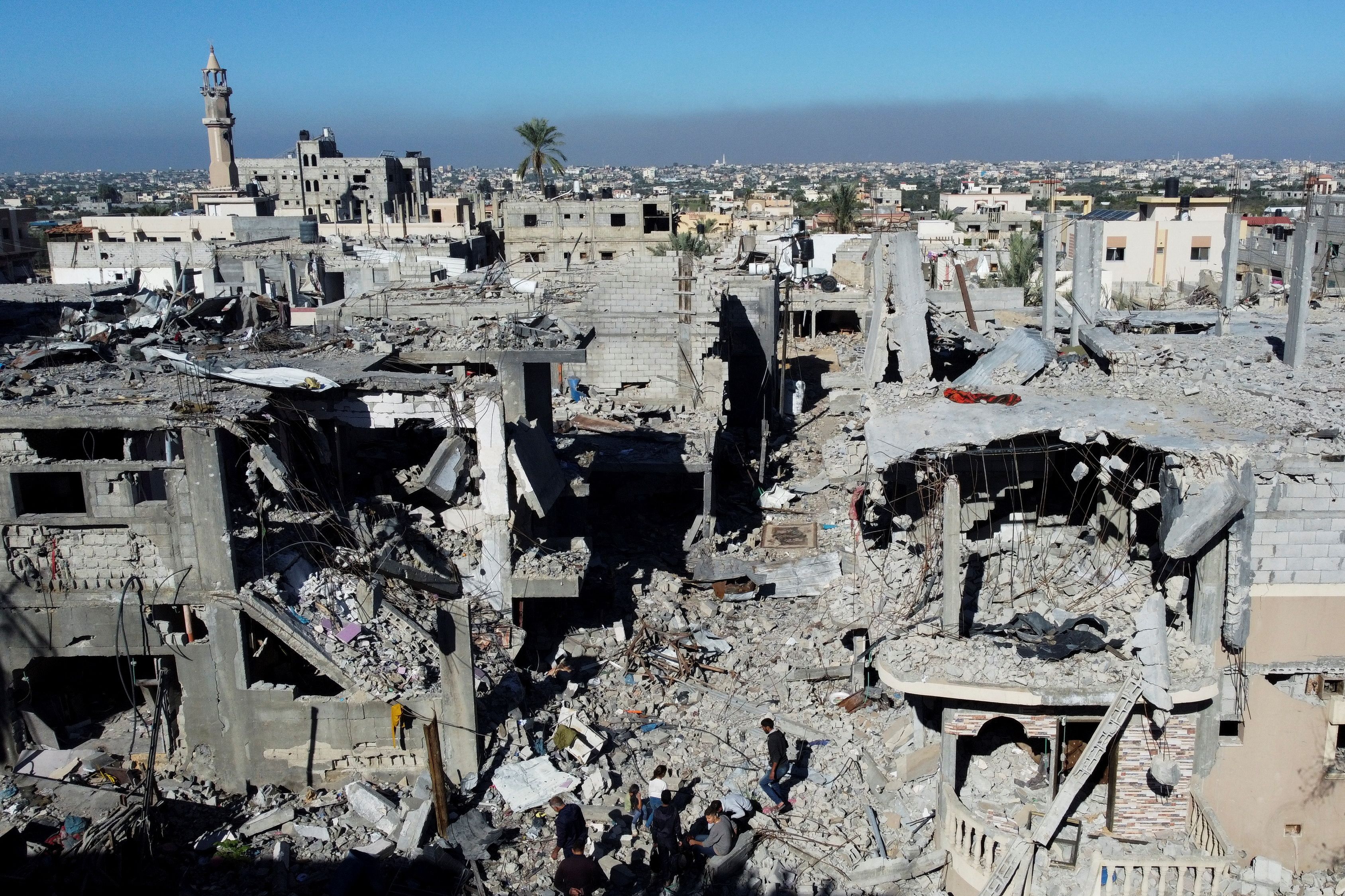 Palestinians walk among the rubble, as they inspect houses destroyed in Israeli strikes during the conflict, amid the temporary truce between Israel and the Palestinian Islamist group Hamas, at Khan Younis refugee camp, in the southern Gaza Strip, November 29, 2023. REUTERS/Mohammed Salem