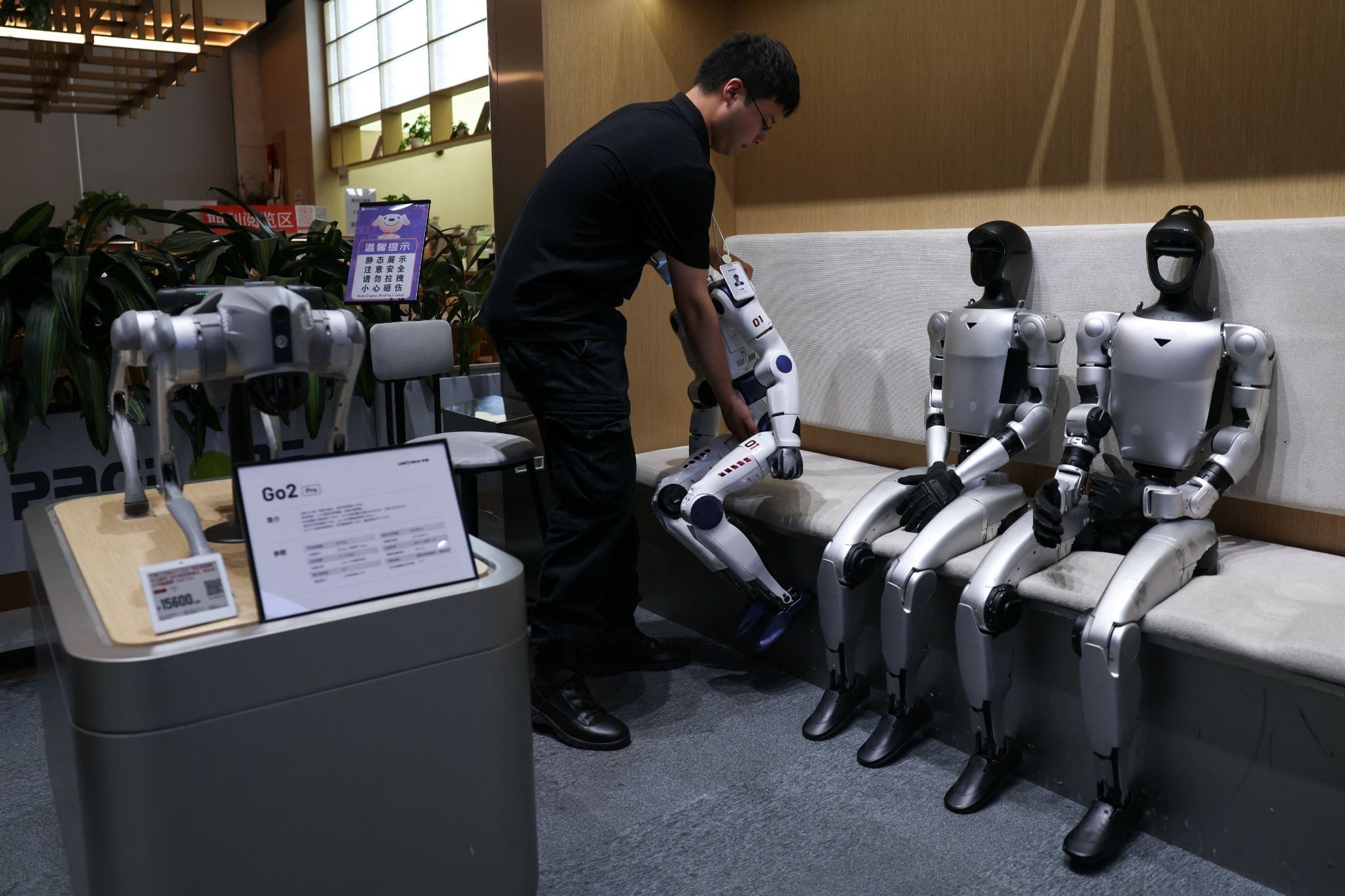 Staff member places a Unitree’s R1 humanoid robot back to seat at a Unitree store in Beijing. 