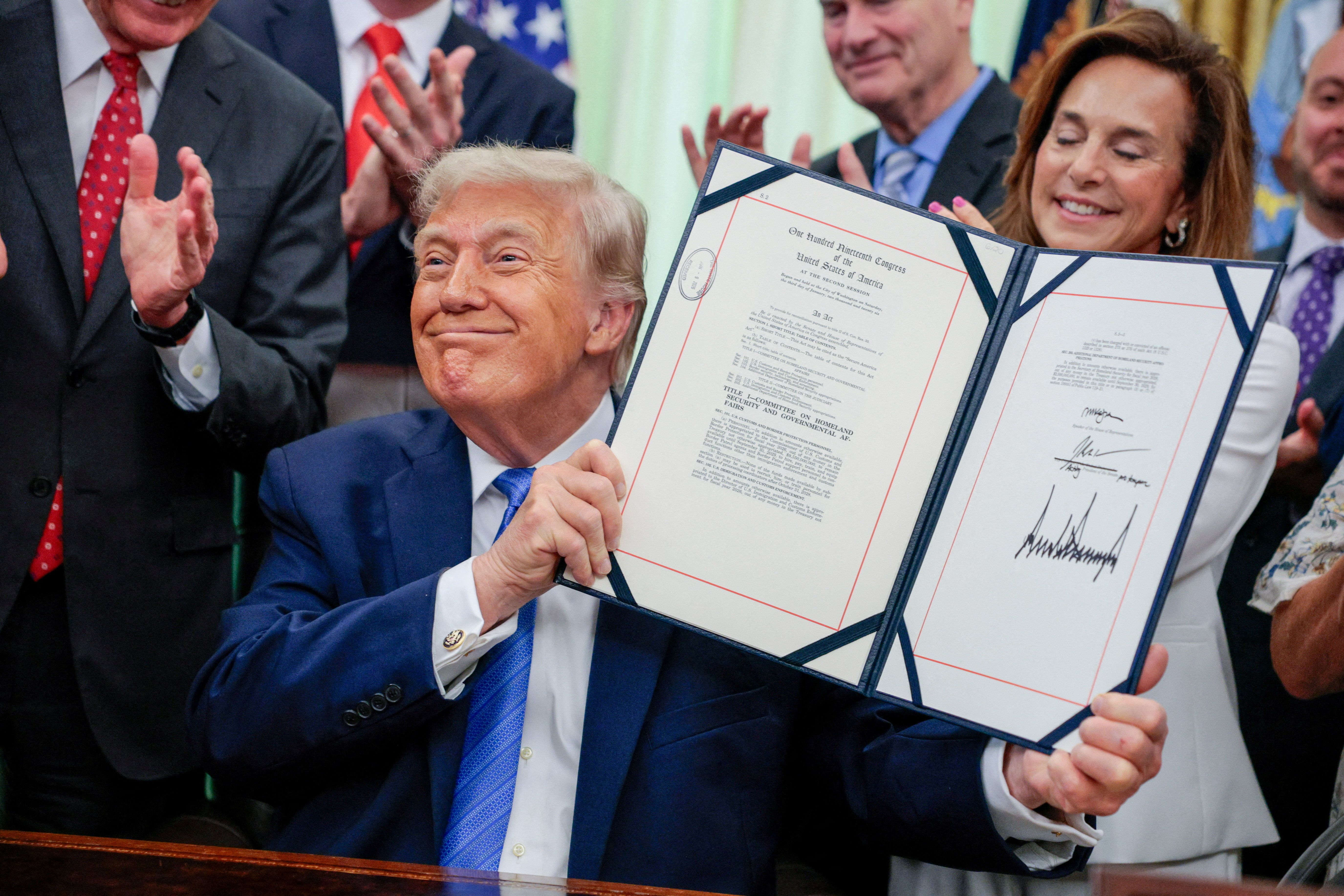 President Donald Trump holds up the Secure America Act