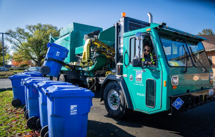 A trash truck collects waste from bins.
