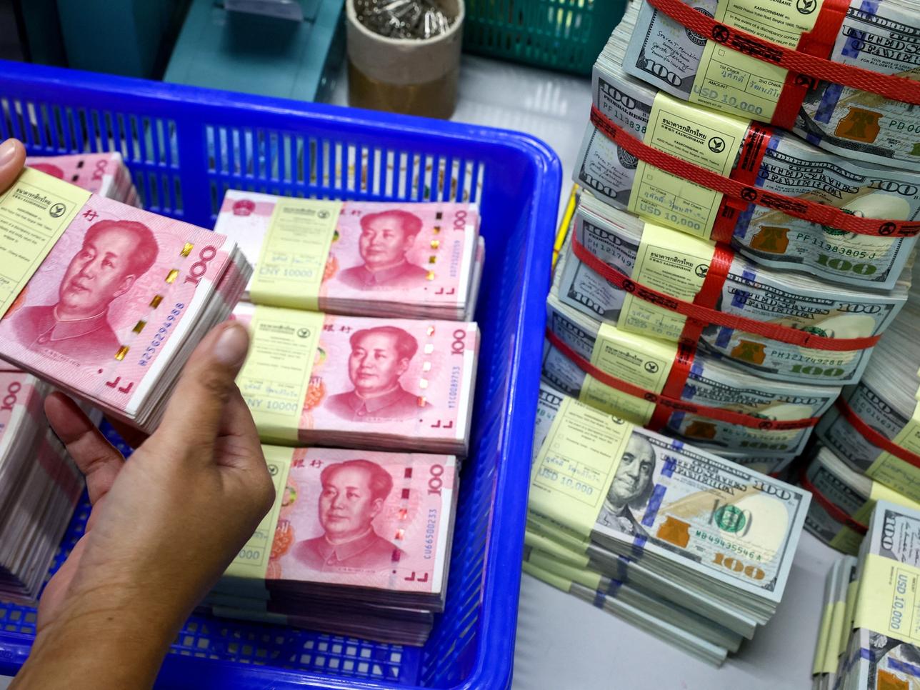 FILE PHOTO: A bank employee counts China's renminbi (RMB) or yuan notes next to U.S. dollar notes at a Kasikornbank in Bangkok, Thailand, January 26, 2023. REUTERS/Athit Perawongmetha/File Photo