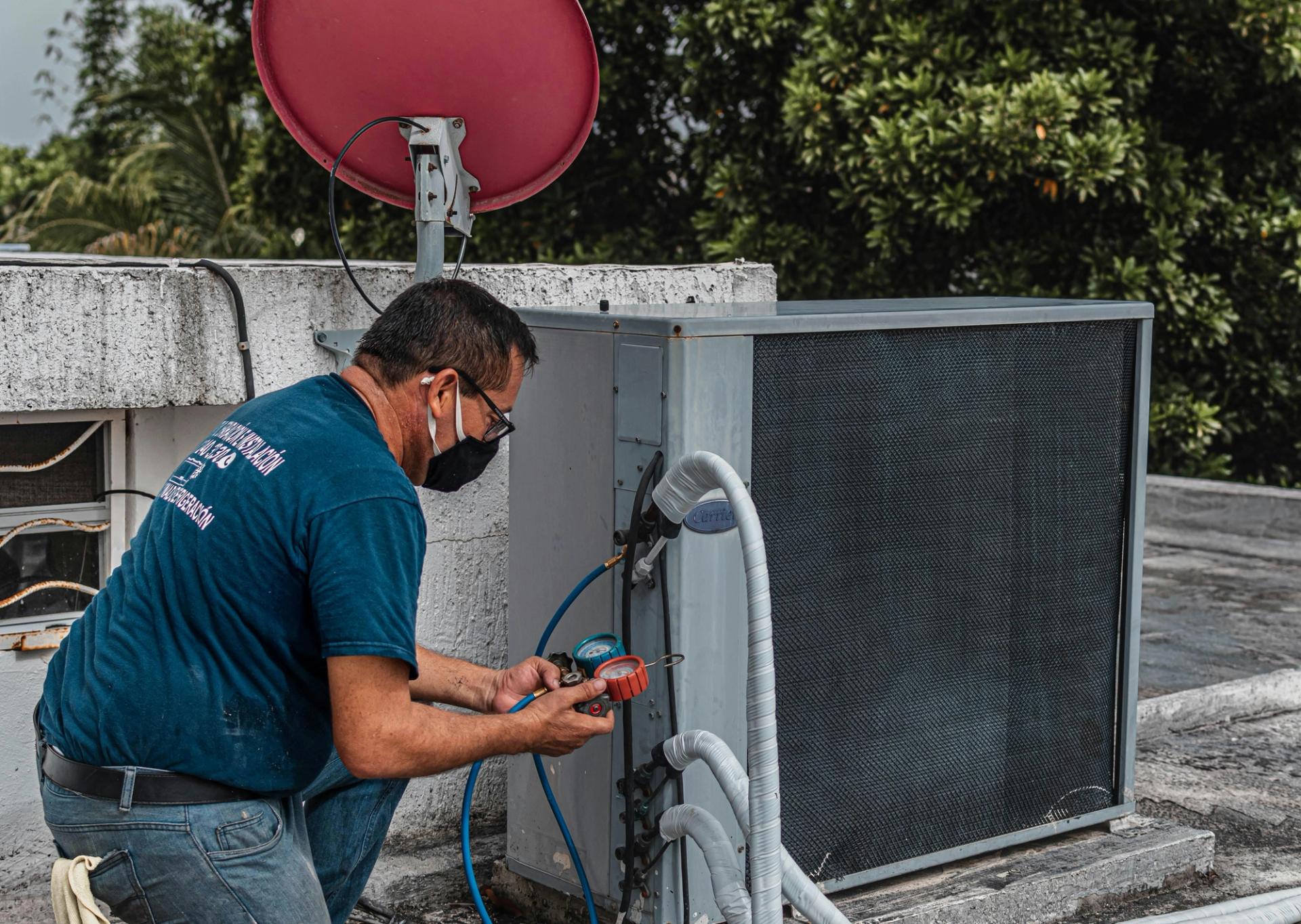 A man checks an air conditioner. 