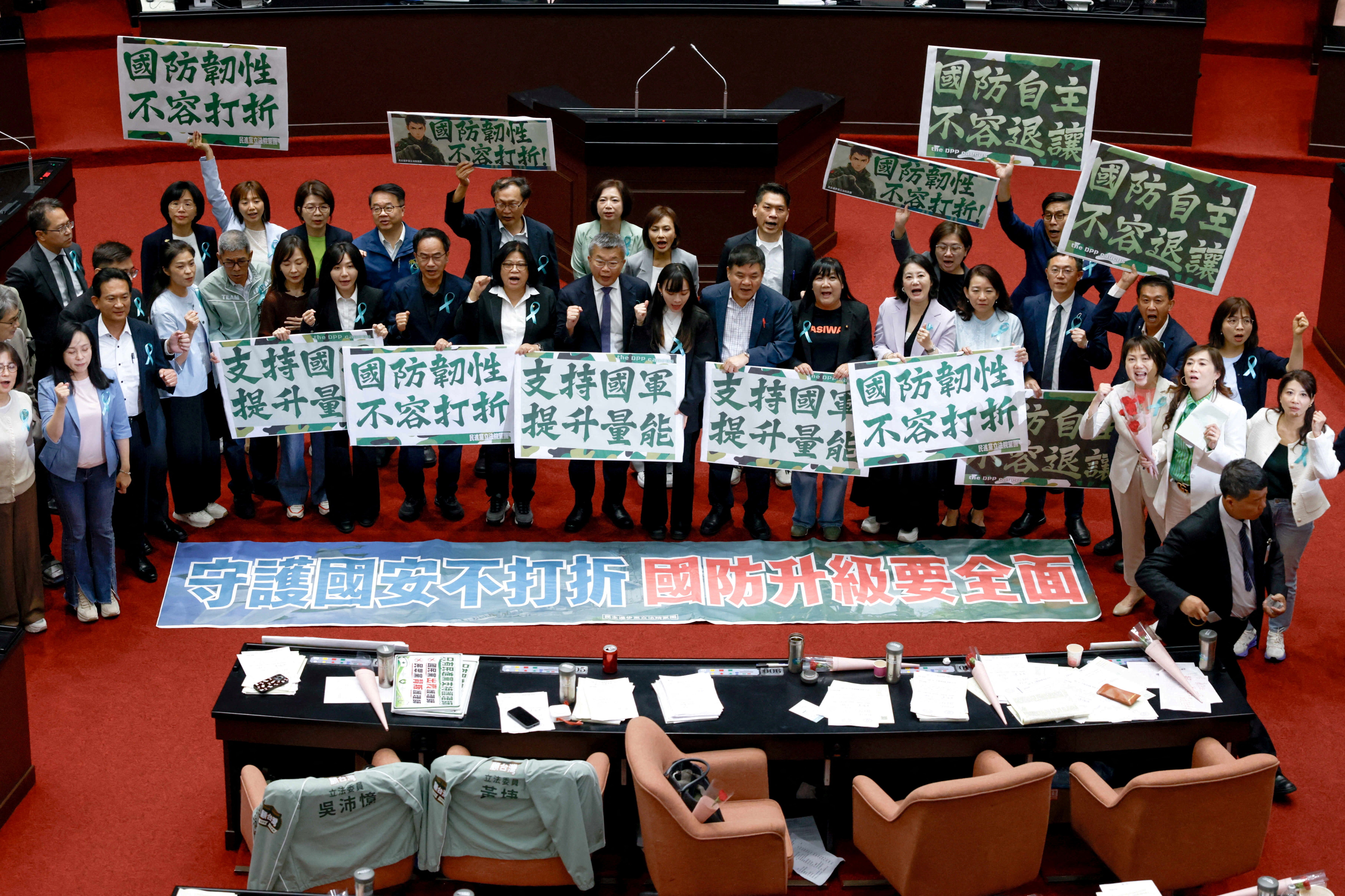 Members of the ruling Democratic Progressive Party (DPP) hold signs after the opposition-controlled parliament approved a $25 billion special defence spending budget, at the Legislative Yuan in Taipei