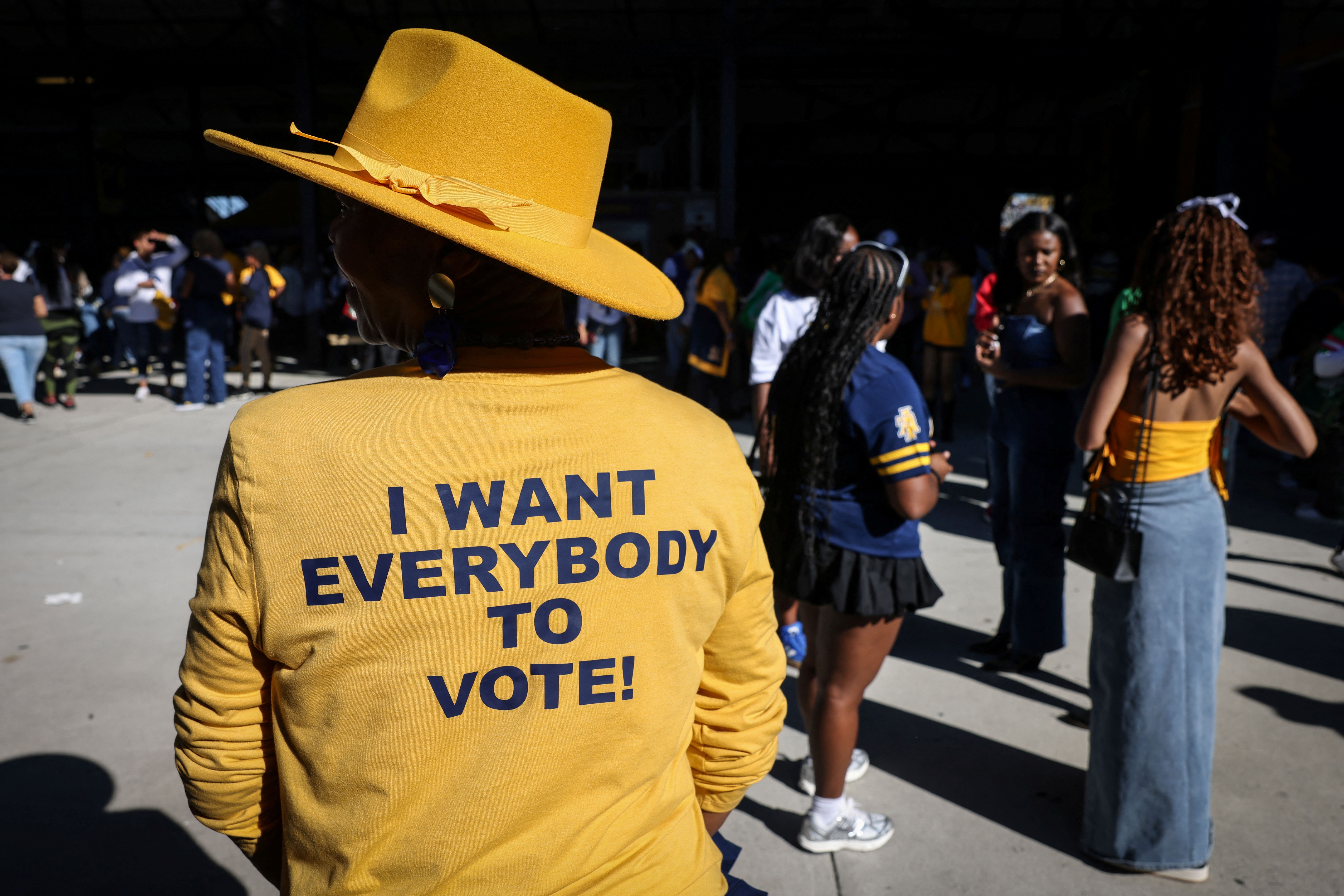 A woman wears a yellow shirt that reads “I want everybody to vote!” ahead of the US election.