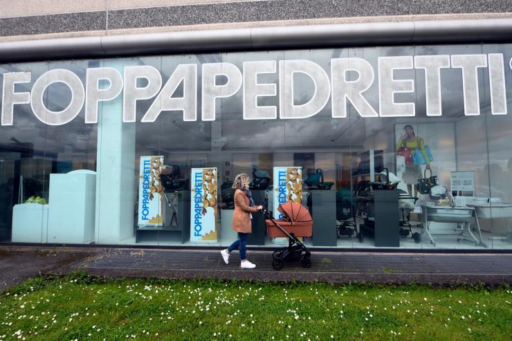 A woman pushing a baby stroller walks past the showroom of manufacturer Foppapedretti’s factory in Bolgare, near Bergamo, Italy.