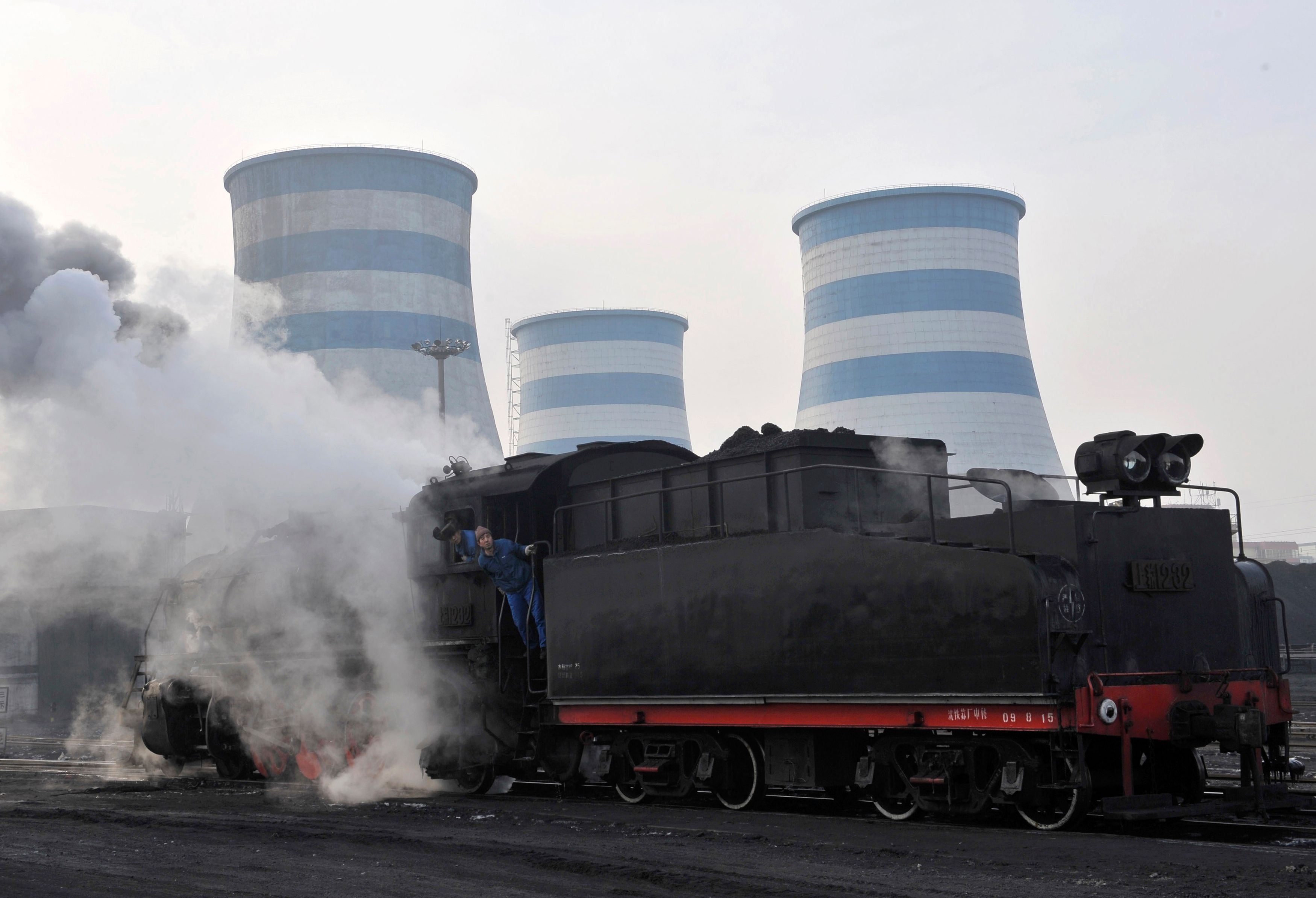 Labourers look out of a steam train transporting coal at a power plant in Shenyang, Liaoning province, China.