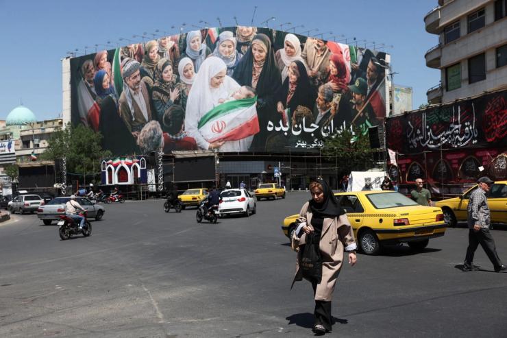 People walk past a billboard in Tehran.
