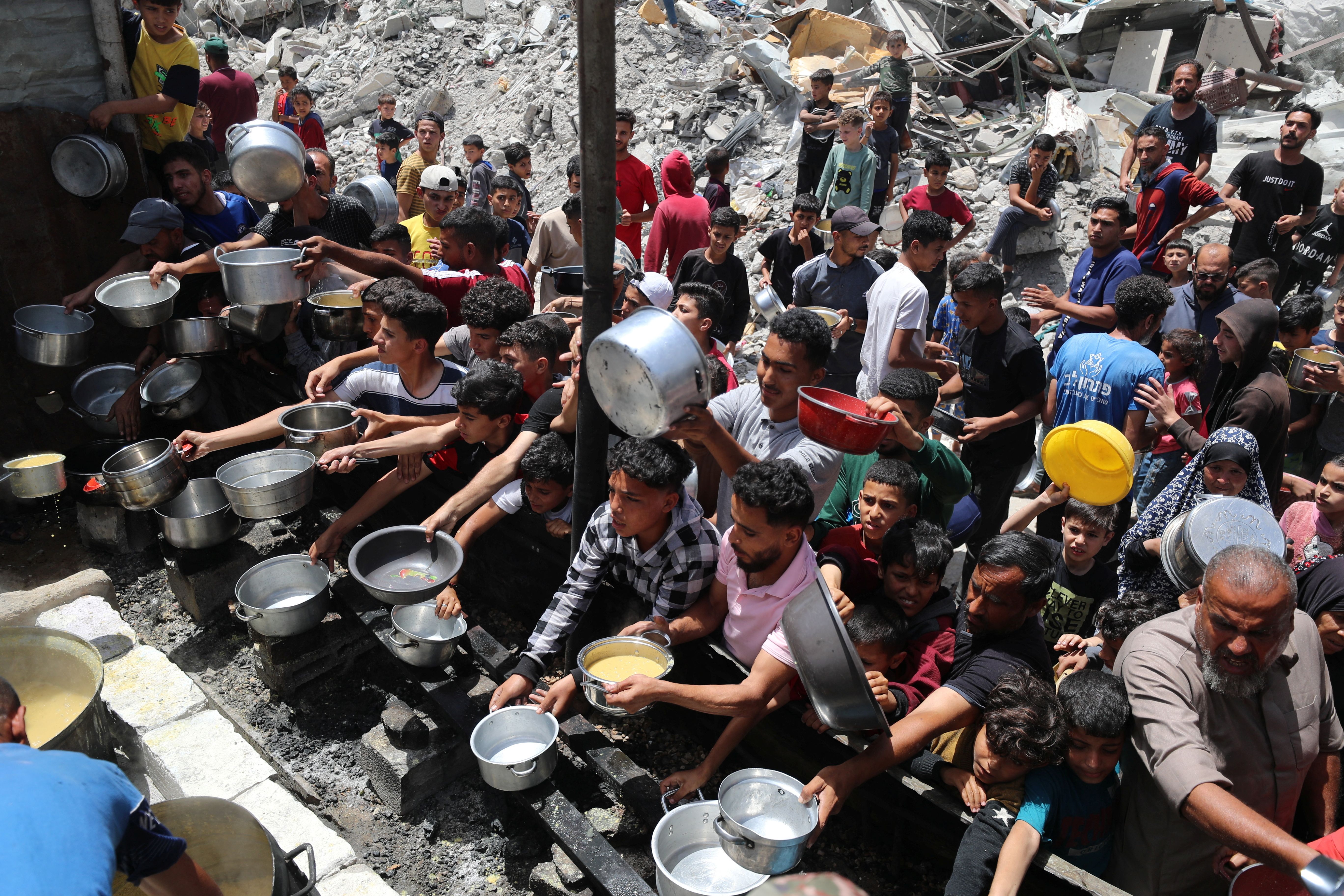 Palestinians wait to receive food cooked by a charity kitchen, in Jabalia, in the northern Gaza.