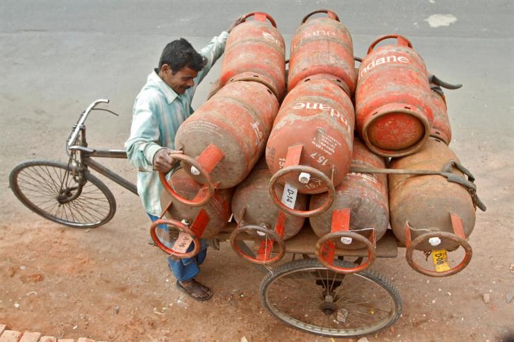A worker loads Liquefied Petroleum Gas (LPG) cylinders onto his cycle-rickshaw in Kolkata