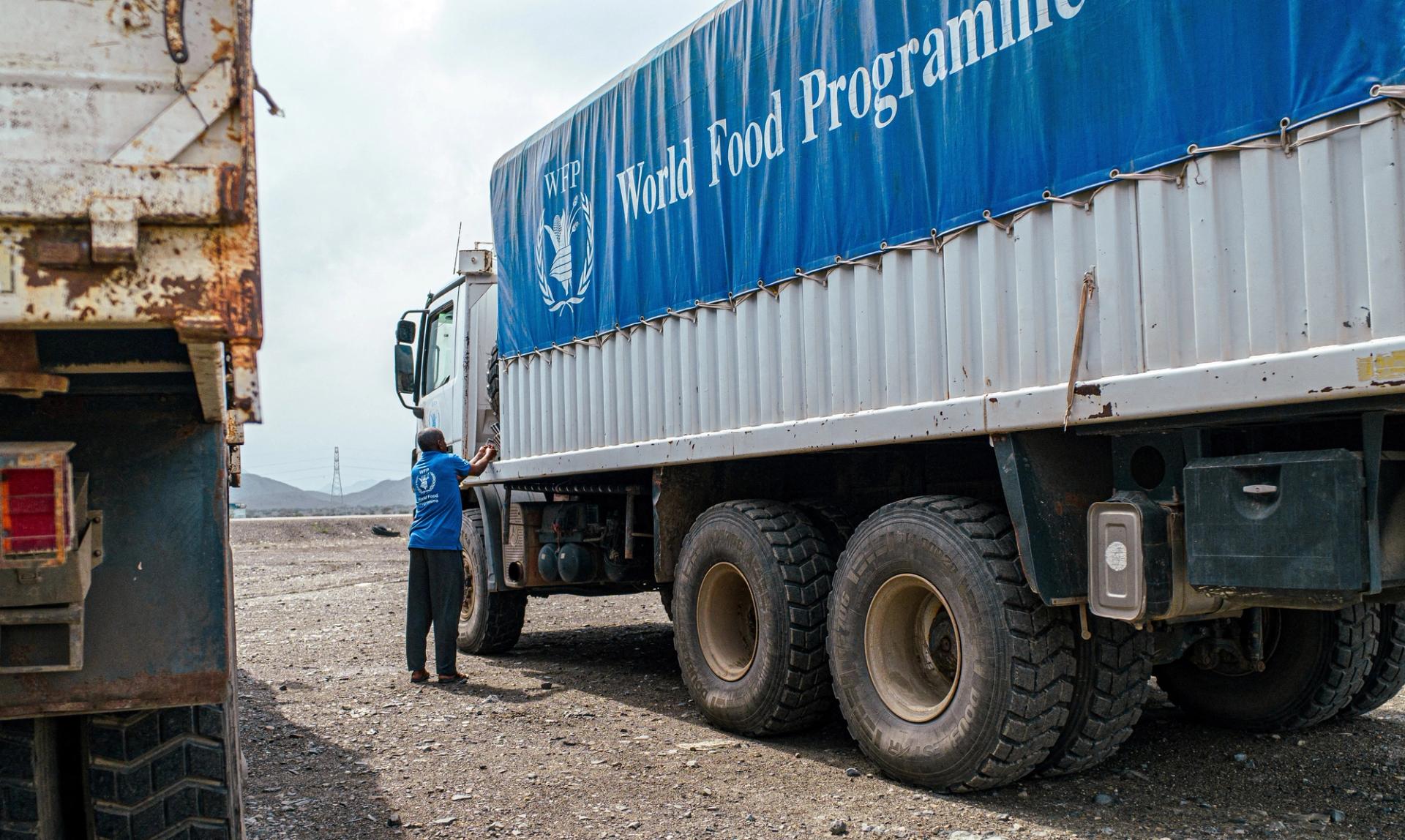 A World Food Program worker stands next to a truck carrying aid headed to Darfur in November.