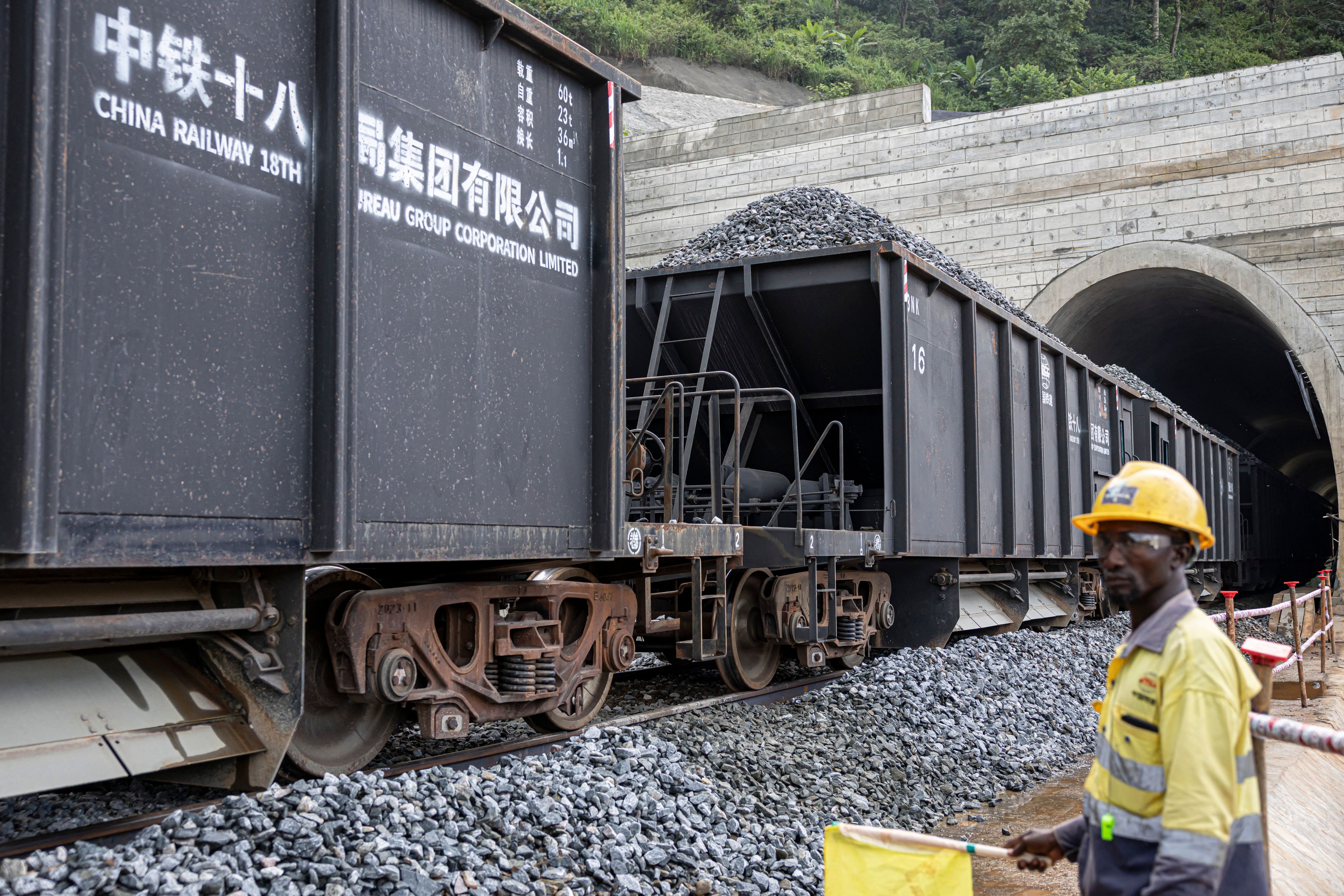 A China Railway 18th Bureau Group employee watches as a train transports rocks at the SimFer mining complex in Guinea.