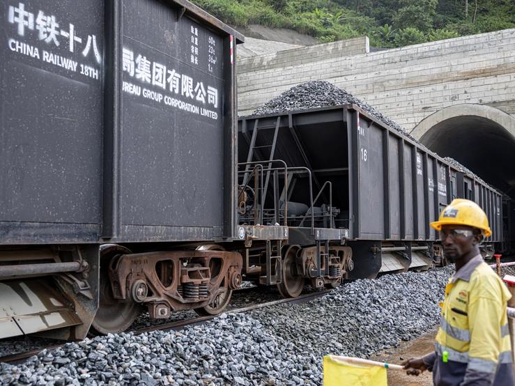 A China Railway 18th Bureau Group employee watches as a train transports rocks at the SimFer mining complex in Guinea.