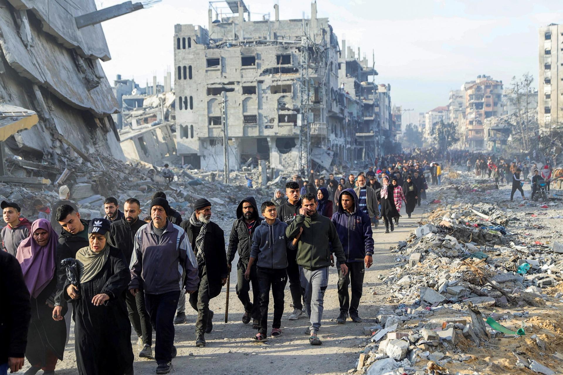 Displaced Palestinians make their way past the rubble as they return to their homes Sunday.