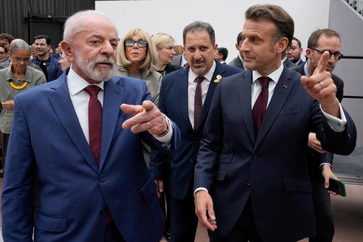 A photo of Lula and Macron pointing in different directions.