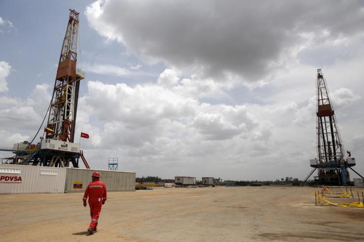 An oilfield worker walks next to drilling rigs at an oil well operated by Venezuela’s state oil company PDVSA, in the oil rich Orinoco belt, near Morichal at the state of Monagas April 16, 2015. Picture taken on April 16, 2015.