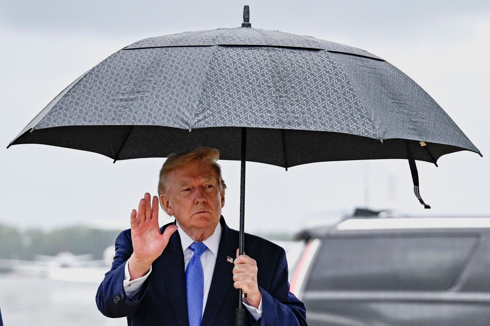 US President Donald Trump gestures as he holds an umbrella after disembarking Air Force One at Joint Base Andrews, in Maryland, US.