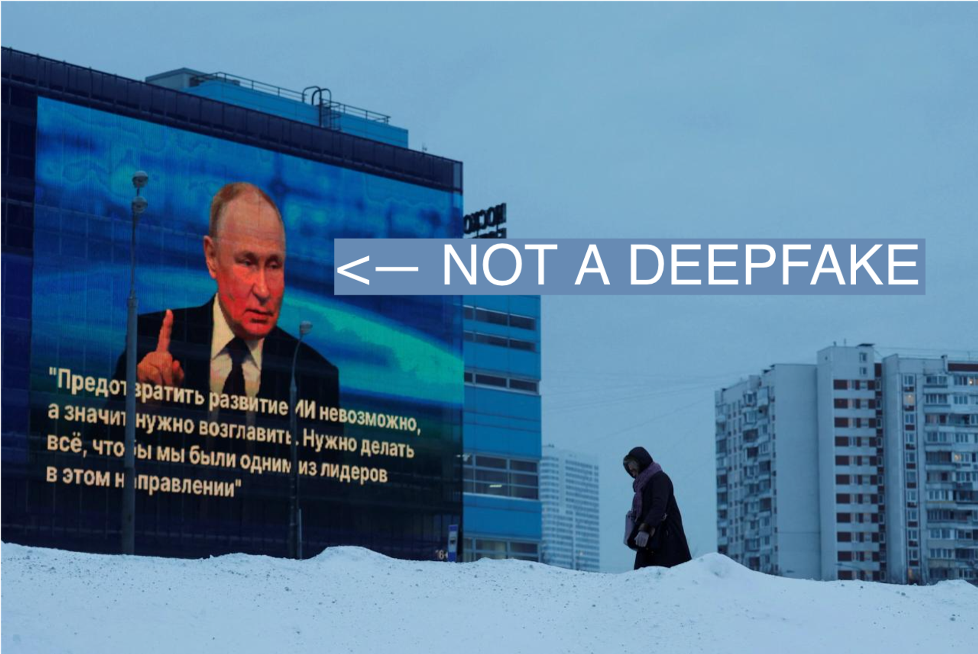 A woman walks past an electronic screen on the facade of a building showing an image of Russian President Vladimir Putin and a quote from his annual end-of-year press conference and the Direct Line question and answer session.