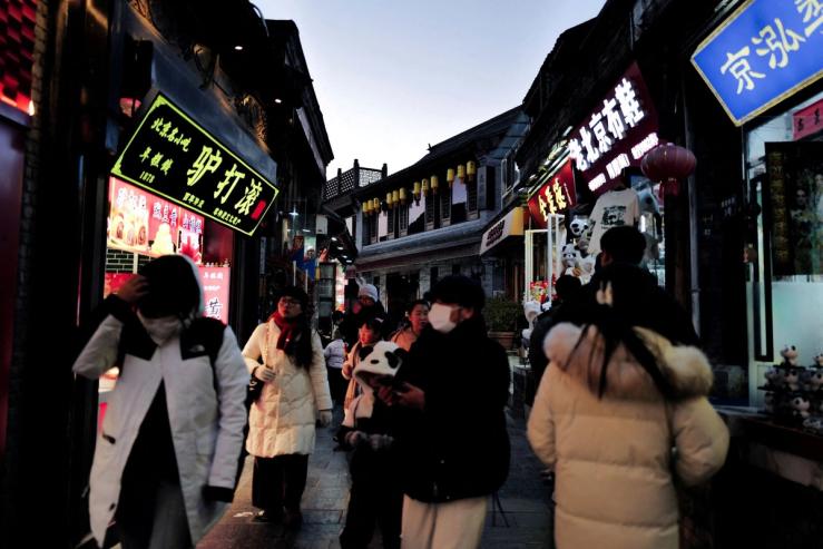 People walk down a commercial street in Beijing.