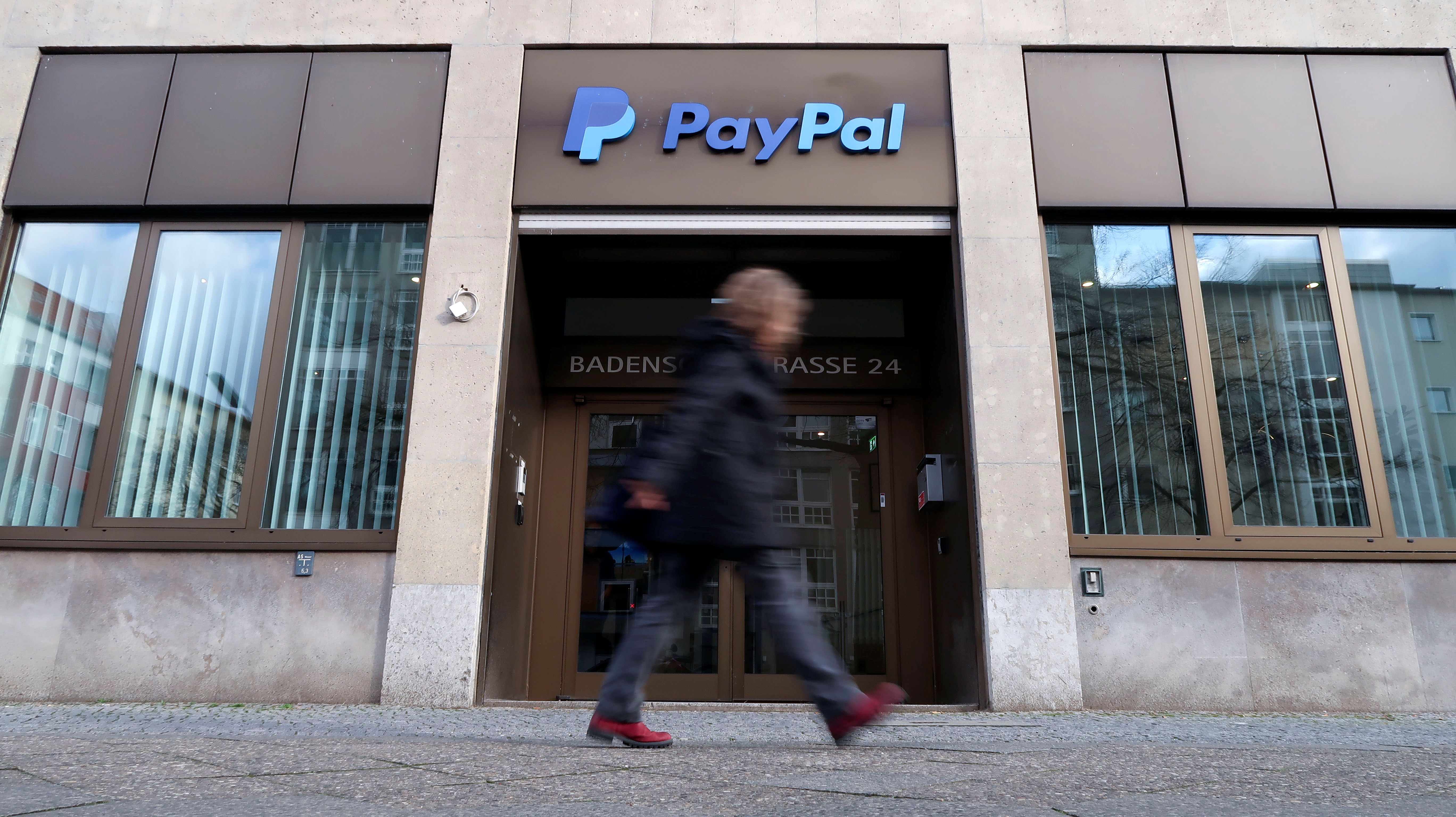 A pedestrian walks past the PayPal logo at an office building in Berlin.
