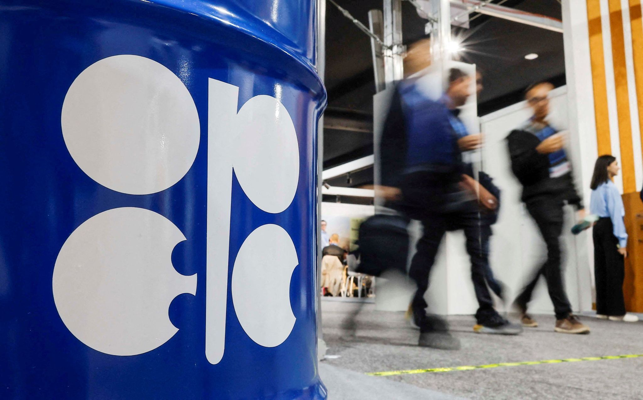 People walk past an installation depicting barrel of oil with the logo of Organization of the Petroleum Exporting Countries at COP29.