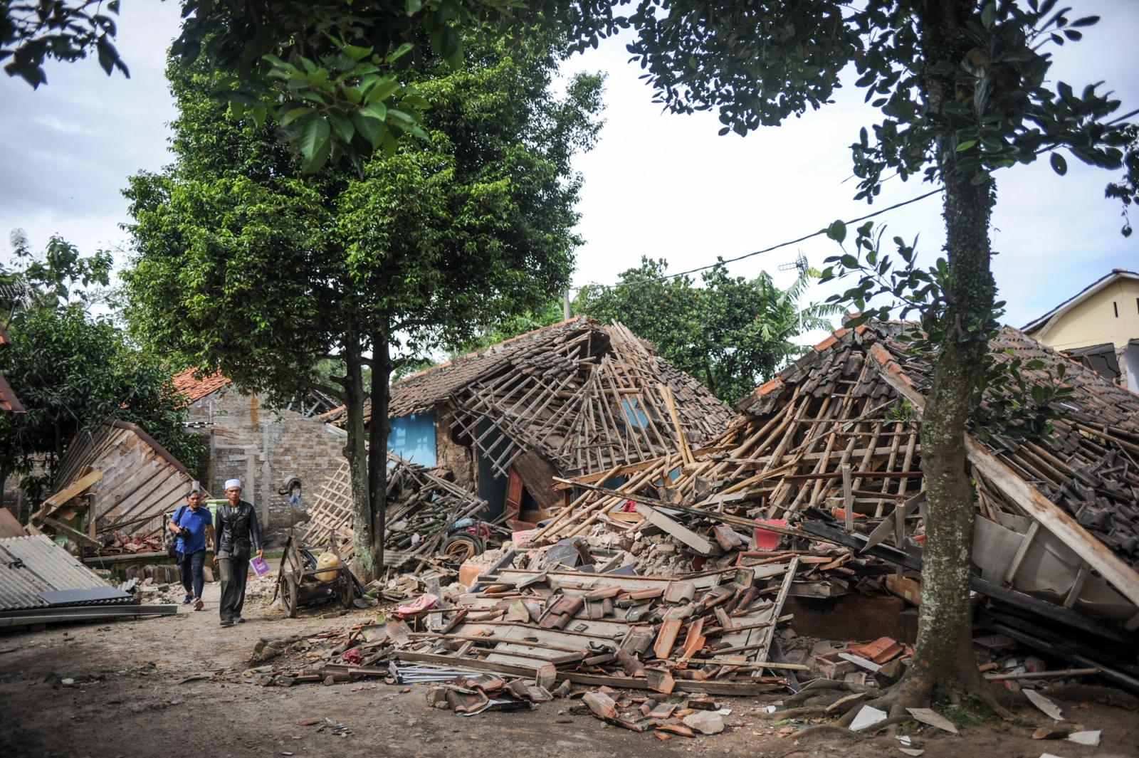 Locals walk past collapsed houses after an earthquake in Cianjur, West Java province, Indonesia, November 22, 2022.
