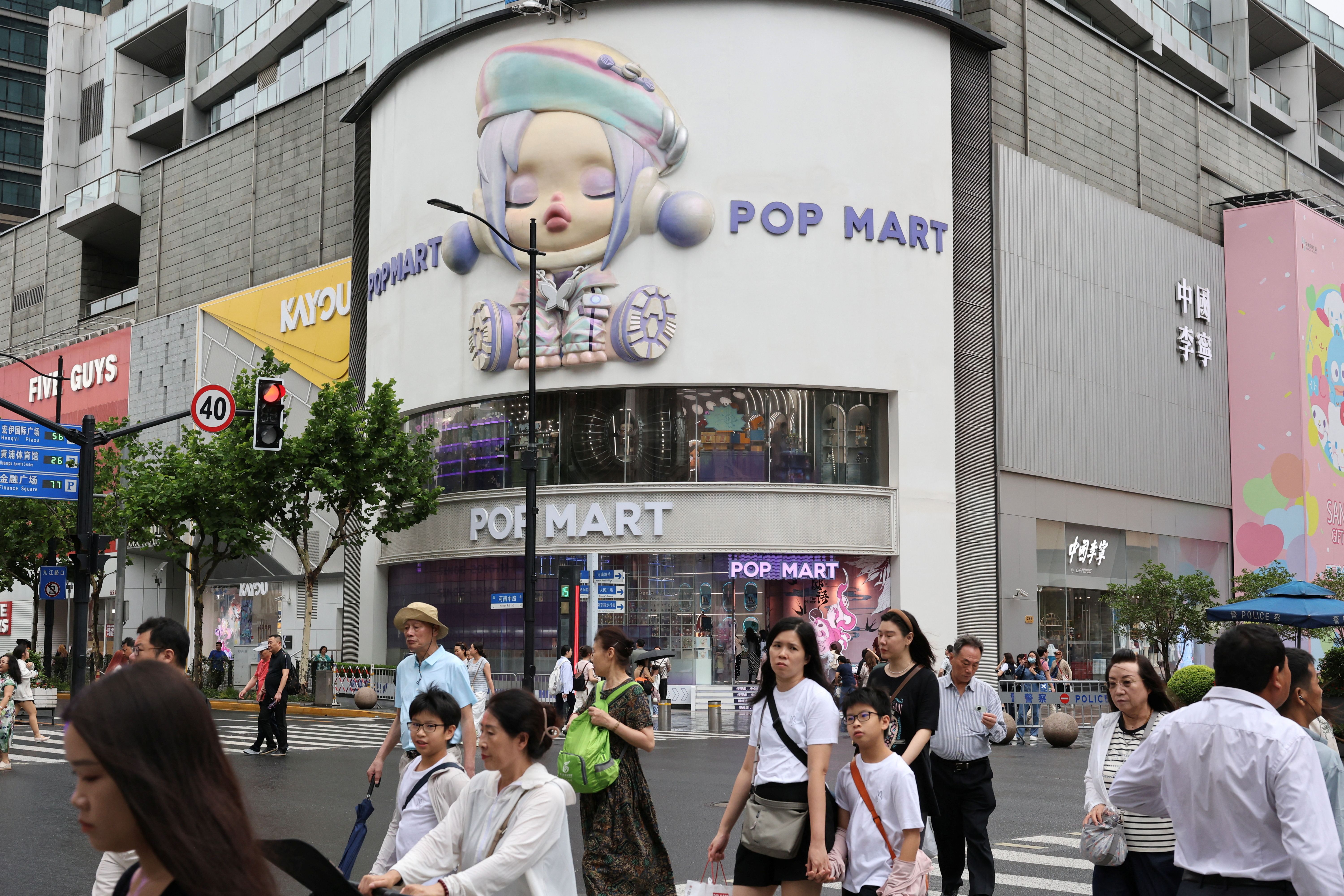 People walk on a crosswalk in front of the Pop Mart’s flagship store in Shanghai, China.