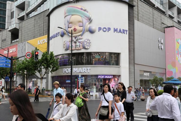 People walk on a crosswalk in front of the Pop Mart’s flagship store in Shanghai, China.