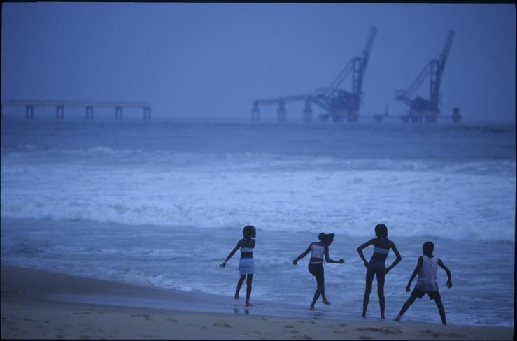 Children playing on the beach, facing oil equipment in Pointe Noire, Congo.