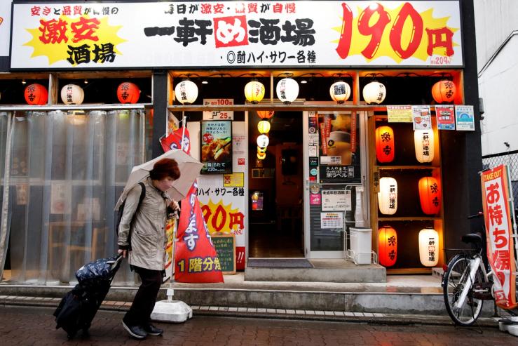 A woman walks in front of a cheap izakaya (Japanese tavern) in Tokyo, Japan.