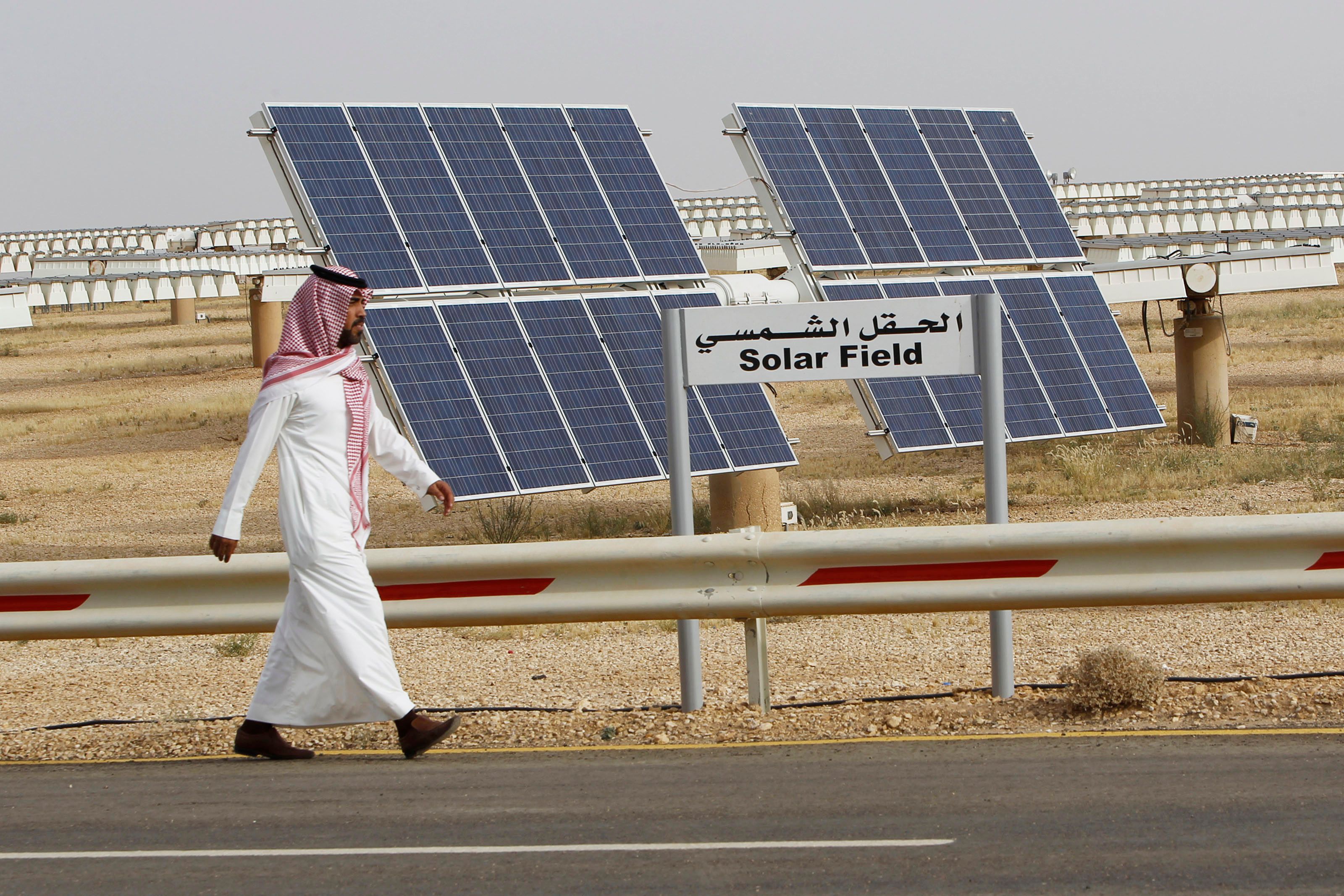 A Saudi man walks on a street past a field of solar panels at the King Abdulaziz city of Sciences and Technology, Al-Oyeynah Research Station.