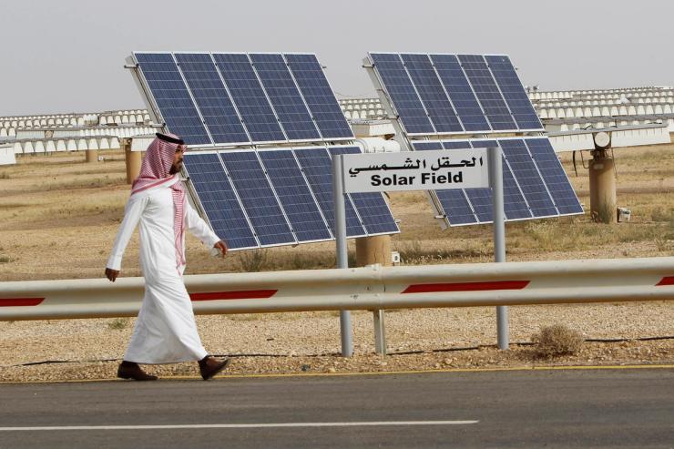 A Saudi man walks on a street past a field of solar panels at the King Abdulaziz city of Sciences and Technology, Al-Oyeynah Research Station.