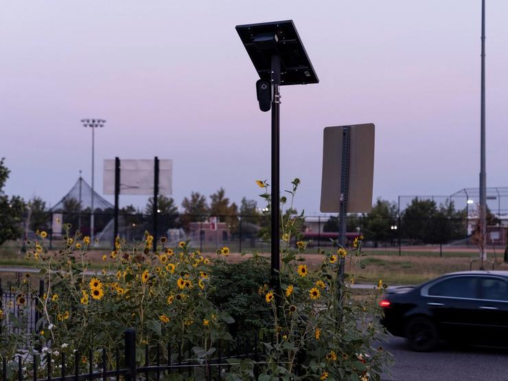 A Flock Safety camera is mounted on a pole amid sunflowers in Commerce City, Colorado