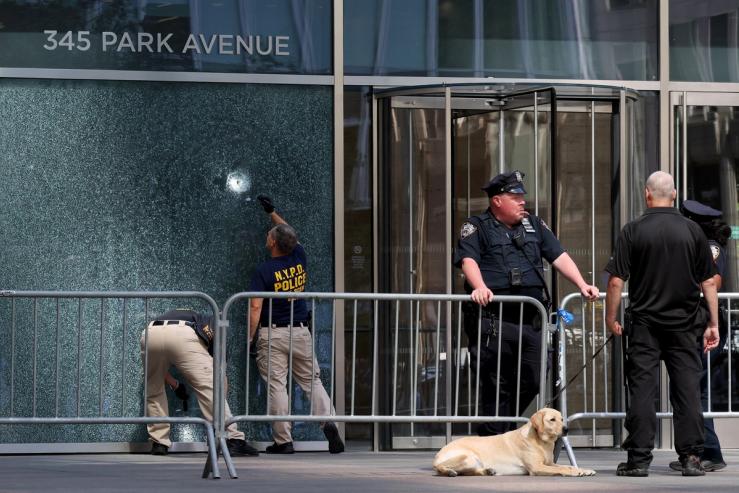 NYPD Crime Scene Unit investigators inspect a bullet hole at the scene of a deadly mass shooting in Manhattan, New York.
