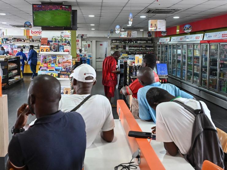 A customer charges his mobile phone as other customers shop at a supermarket in Abidjan on Sept. 20, 2025.