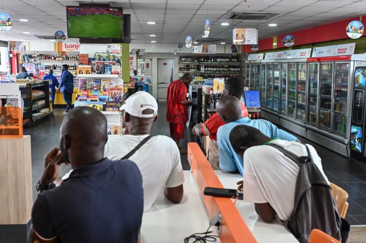 A customer charges his mobile phone as other customers shop at a supermarket in Abidjan on Sept. 20, 2025.