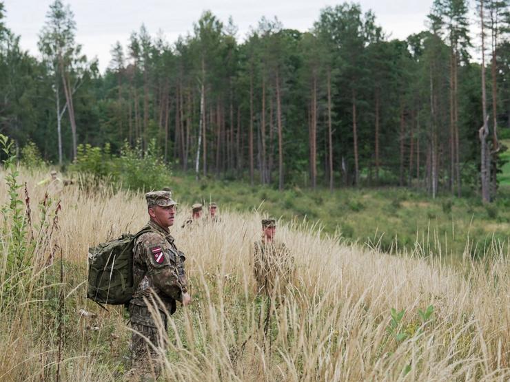 Latvian National Guard walk on a field as they search for debris from a drone intercepted by a NATO fighter.