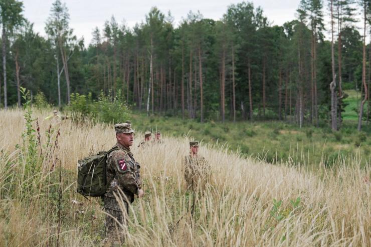 Latvian National Guard walk on a field as they search for debris from a drone intercepted by a NATO fighter.